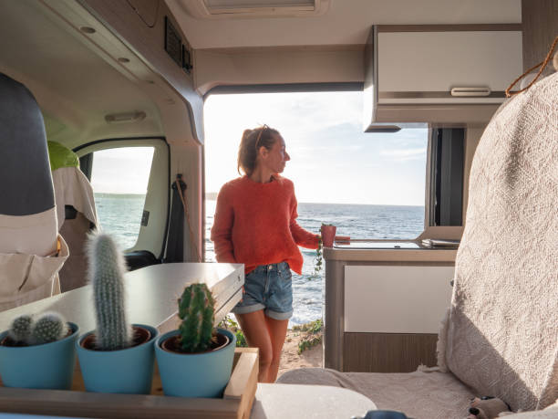 istock Woman relaxing in a van looking at ocean, sunset 1317464209