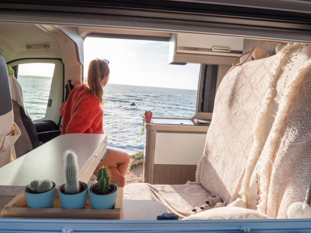 istock Woman relaxing in a van looking at ocean, sunset 1317464211