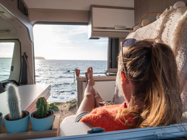 istock Woman relaxing in a van looking at ocean, sunset 1317464270