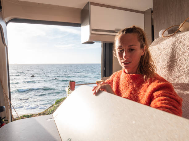 istock Woman relaxing in a van looking at ocean, sunset 1317464298