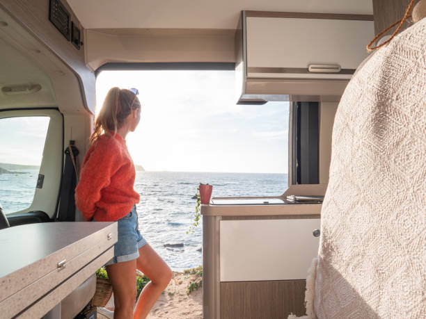 istock Woman relaxing in a van looking at ocean, sunset 1317464299