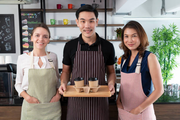 istock Young bartender serving passing hot drinks to customer at coffee shop. Barista passing coffee cups to his customer. Small business, people and service concept. 1317464599