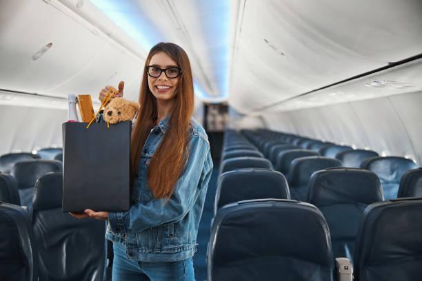 istock Joyful lady on a plane presenting shopping bag with gifts 1317468140