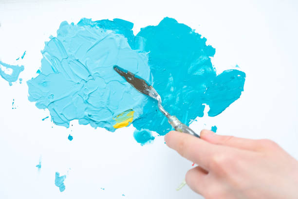 Process of acrylic drawing picture using palette knife. Applying oil paint on canvas with small metal spatula. Blue color of oil paint. Close view.
