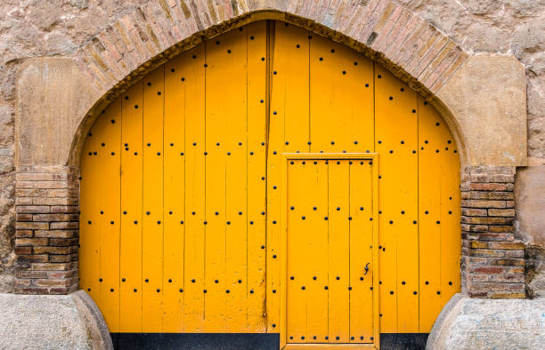 Closeup of a rustic yellow wooden door with arch of a house