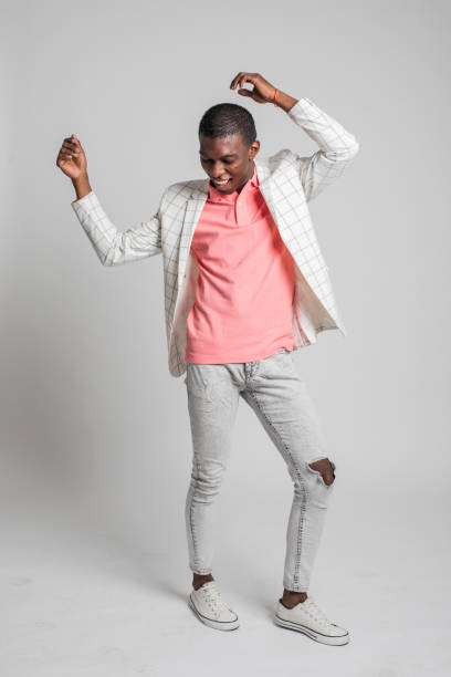 istock Fashionable young man laughs, dances and moves on grey backdrop. 1317473576