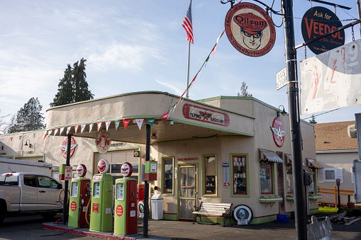 Gladstone, OR, USA - Mar 2, 2021: Restored vintage Flying A Gas Station with a trio of porcelain pumps and a porch swing, now serving as a motorcycle and ATV parts store, in Gladstone, Oregon.