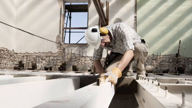 homem no trabalho, pedreiro usa capacete e usa o nível de espírito, verifique as vigas na base das fundações do segundo andar da casa, em construção de reforma fundo - construction frame wood accuracy adult - fotografias e filmes do acervo