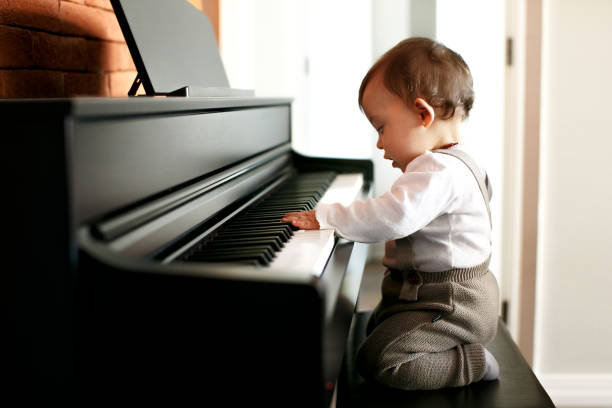 Curitiba, Brazil - June 19, 2020: Toddler girl playing and having fun with an electric piano at home.