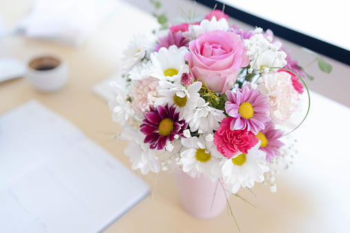Flowers on wooden desk in modern home office stock. Beautiful bouquet of flowers in the office on the table.