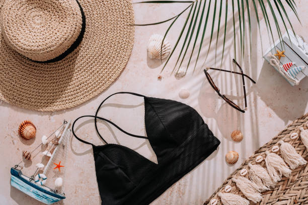 Travel flat lay with bikini, beach accessories, straw hat and shadows. Vacation travel flat lay with bikini, straw hat, sea souvenirs on beige stone background with hard shadows, top view straw bag stock pictures, royalty-free photos & images