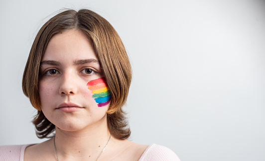 Lesbian short-haired girl, with lgbt flag, painted on her face, on white background