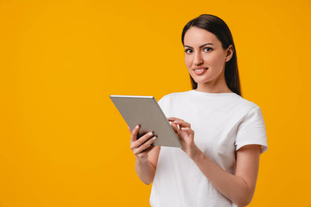 istock Confident smiling young caucasian hispanic student using digital tablet isolated over yellow background. Successful female office worker searching web or watching online webinars 1317479853