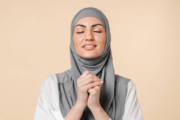 prier en espérant jeune moyen-orient arabe musulman femme islamique en hijab gris demandant de l’aide, mosquée de prière isolée sur fond beige. paroissiens pleins d’espoir - praying islam sacrifice mosque photos et images de collection