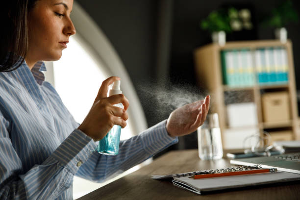 istock Young businesswoman using disinfecting spray and sanitizing her hands 1317482707