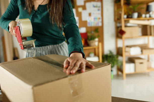 istock Woman taping shut a cardboard box while packing customer's order 1317485973