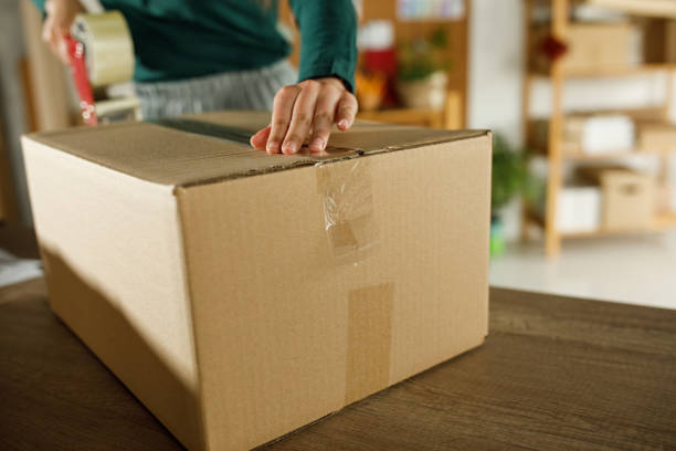 istock Female entrepreneur taping a cardboard box at her desk 1317486027
