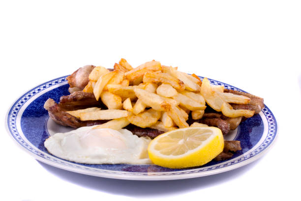 Close up view of a bunch of fried potatoes in slices, with egg and roasted meat.