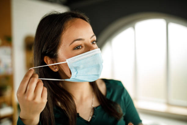 istock Young woman taking off a protective face mask she is wearing 1317487092
