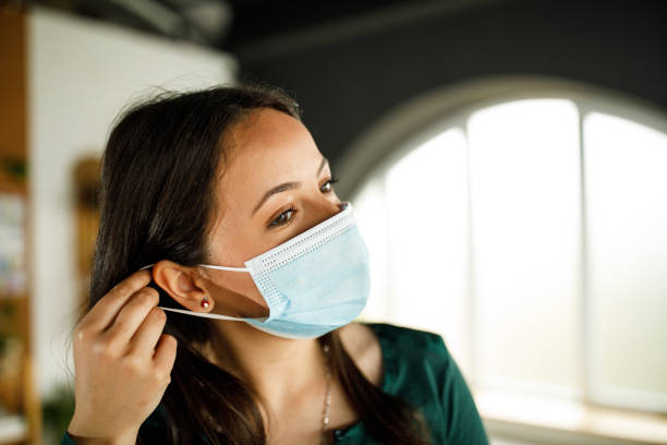 Young woman putting on a protective face mask