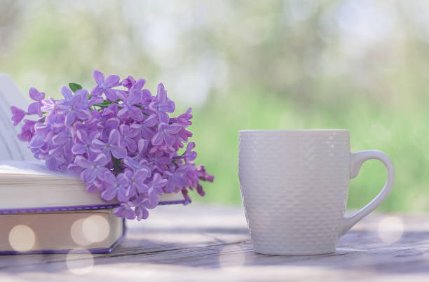 istock blooming lilacs on a book and a white cup on a table 1317488262