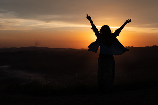girl silhouette with arms up with and a beautiful sunset