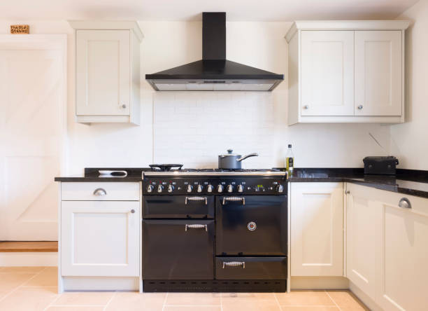 Modern modular kitchen interior, range cooker and chimney hood Modern modular kitchen interior in black and off white, with range cooker and chimney extractor hood. UK painted wood farmhouse kitchen design. kitchen hood stock pictures, royalty-free photos & images