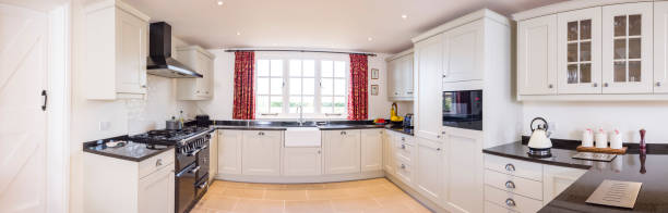 Modular painted wood kitchen panorama, panoramic, UK kitchens Modular painted wood kitchen, panoramic of modern UK farmhouse kitchen with neutral units and black granite worktops white units stock pictures, royalty-free photos & images