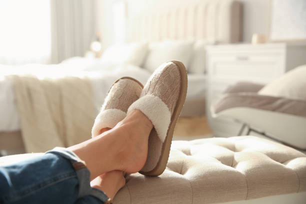 donna che indossa morbide pantofole comode a casa, primo piano - bed human leg home interior comfortable foto e immagini stock