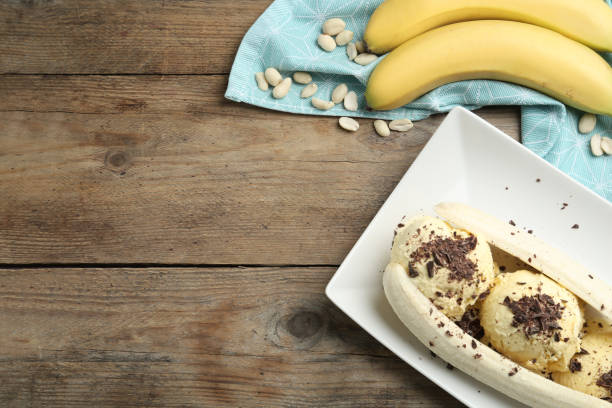 istock Delicious banana split ice cream on wooden table, flat lay. Space for text 1317492960