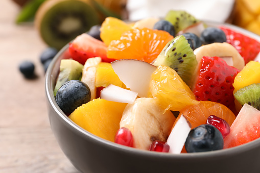 Delicious fresh fruit salad in bowl on table, closeup