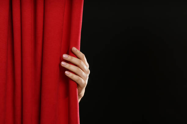 istock Woman opening red front curtains on black background, closeup. Space for text 1317495408
