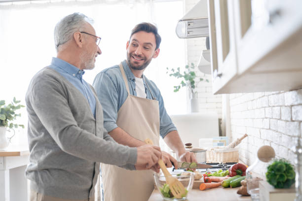 istock Happy young caucasian son talking with his old elderly senior father while cooking dinner, lunch in the kitchen. Preparing food meal together. Happy father`s day! I love you, dad! 1317495752