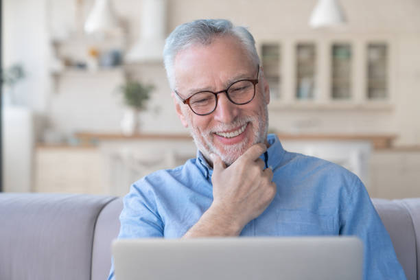 istock Confident handsome grey-haired senior man watching movie on laptop, searching web, doing online shopping, e-learning, watching webinars at home. Home office 1317496823