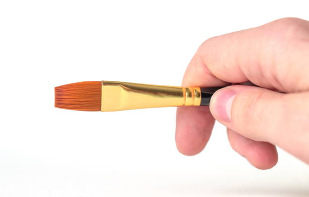 istock A man's hand holds paintbrush on a white background in close-up. Copy space 1317498362