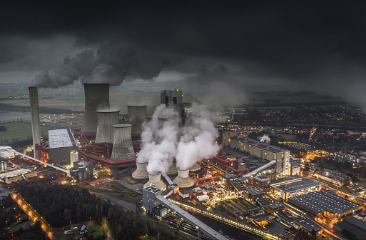 Aerial view of emissions rising from the cooling towers of a lignite fired power station in Germany. Dark clouds at dusk.