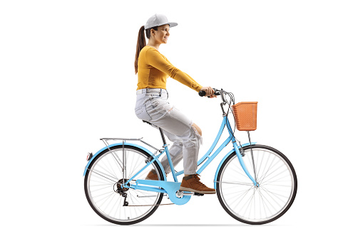 Full length profile shot of a young female riding a blue city bicycle isolated on white background