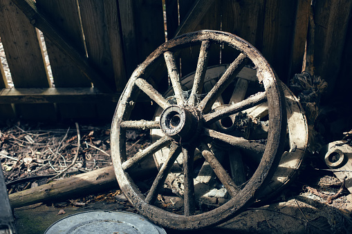 wooden cart wheel stands in an old barn