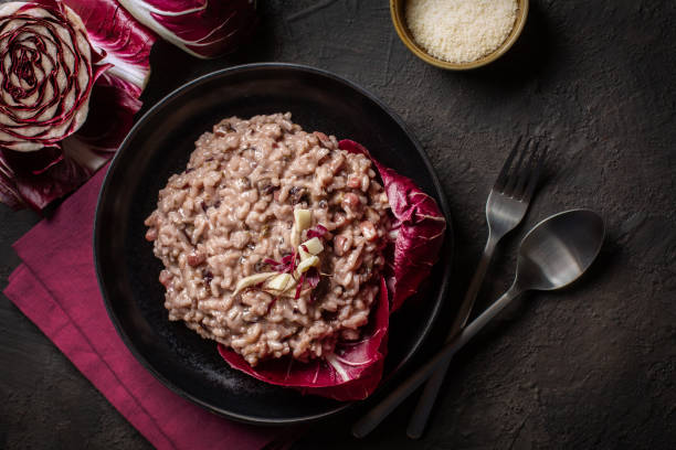 Italian risotto with radicchio rosso di Treviso, pancetta and taleggio cheese. Dark mood foto. Top view. Italian risotto with radicchio rosso di Treviso, pancetta and taleggio cheese. Dark mood foto. Top view. chicory stock pictures, royalty-free photos & images