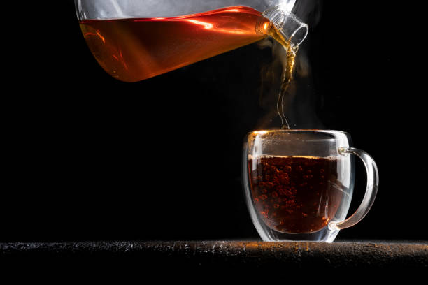 istock Hot tea pours into a transparent mug on a black background 1317502866