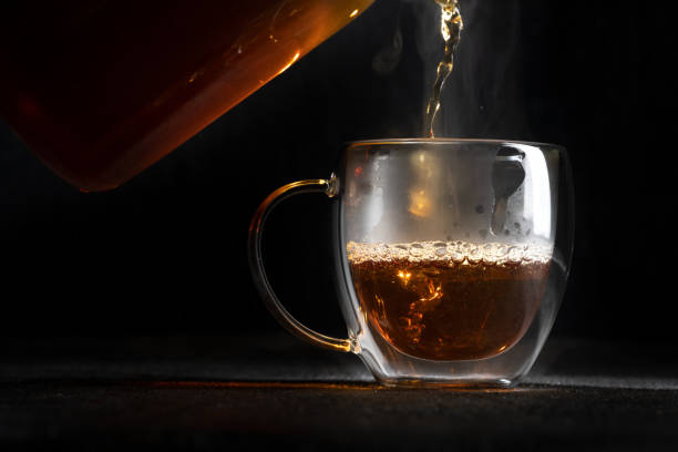 istock Hot tea pours into a transparent mug on a black background 1317502870