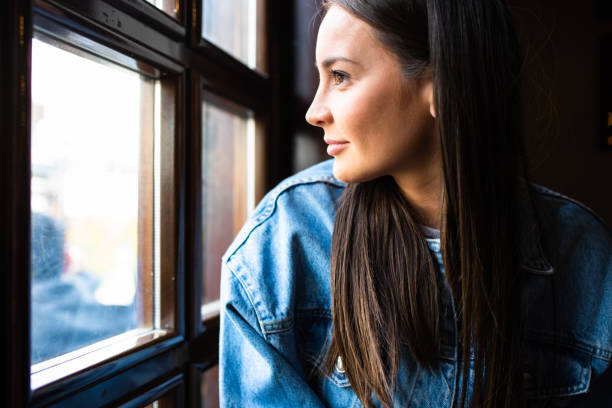istock A beautiful young woman looking out the window smiling 1317503048
