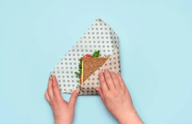 Photo of Wrapping sandwich in a beeswax cloth, top view. Ethical consumerism.