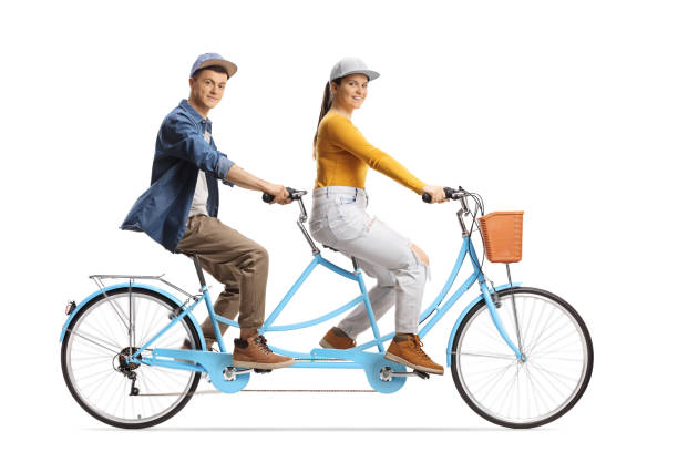 istock Guy and girl riding a tandem bicycle and looking at camera 1317505415