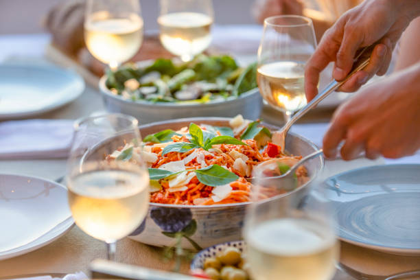 Close up of Serving spaghetti Bolognese on a table at sunset. Close up of Serving spaghetti Bolognese on a table at sunset. There are glasses of wine and salad on the table restaurant place setting dinner dinner party stock pictures, royalty-free photos & images