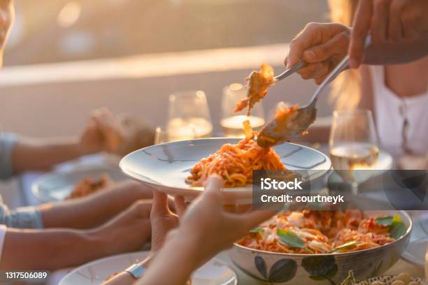 Friends Serving Spaghetti Bolognese On A Table At Sunset There Are Glasses Of Wine And Salad On The Table Close Up Tight Crop Stock Photo - Download Image Now
