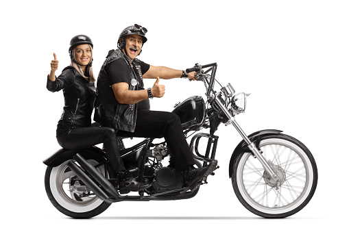 Full length profile shot of a biker riding a young woman on a chopper and showing thumbs up isolated on white background