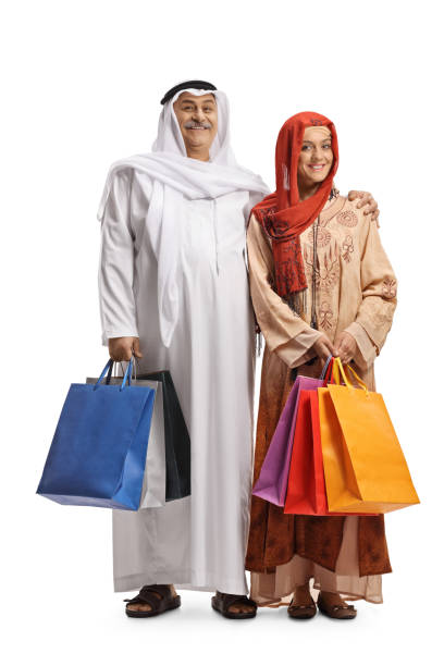 full length portrait of a mature arab man and a young muslim woman holding shopping bags - headscarf islam senior adult east imagens e fotografias de stock