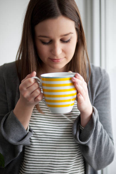 istock Beautiful young woman drinking tea by the window 1317506468