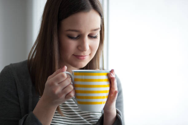 istock Beautiful young woman drinking tea by the window 1317506548